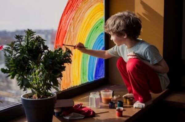 Un enfant qui peint sur une fenêtre. 