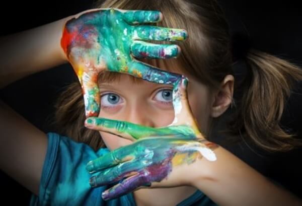Une jeune fille avec les doigts colorés à la peinture.
