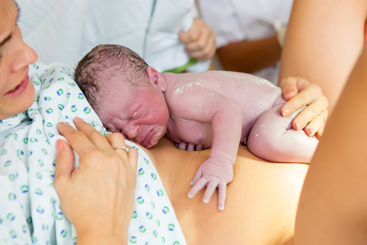 Nyfødt baby på sin moders mave
