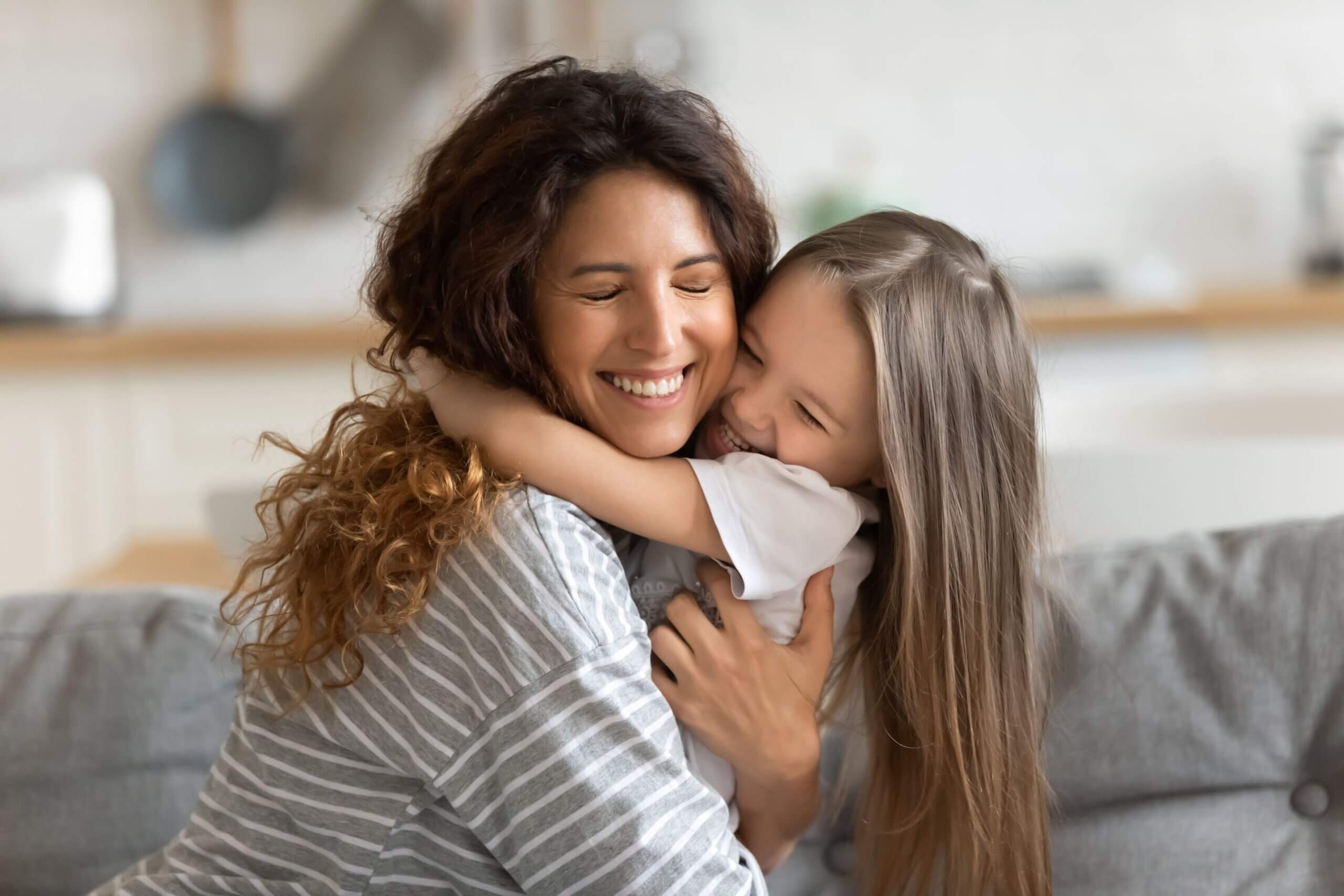 A mother and daughter hugging and smiling.