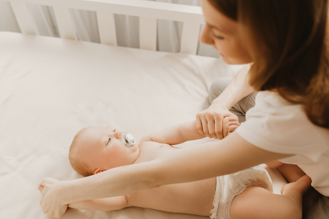mama mueve brazos del bebe en distintas posiciones decubito dorsal acostado