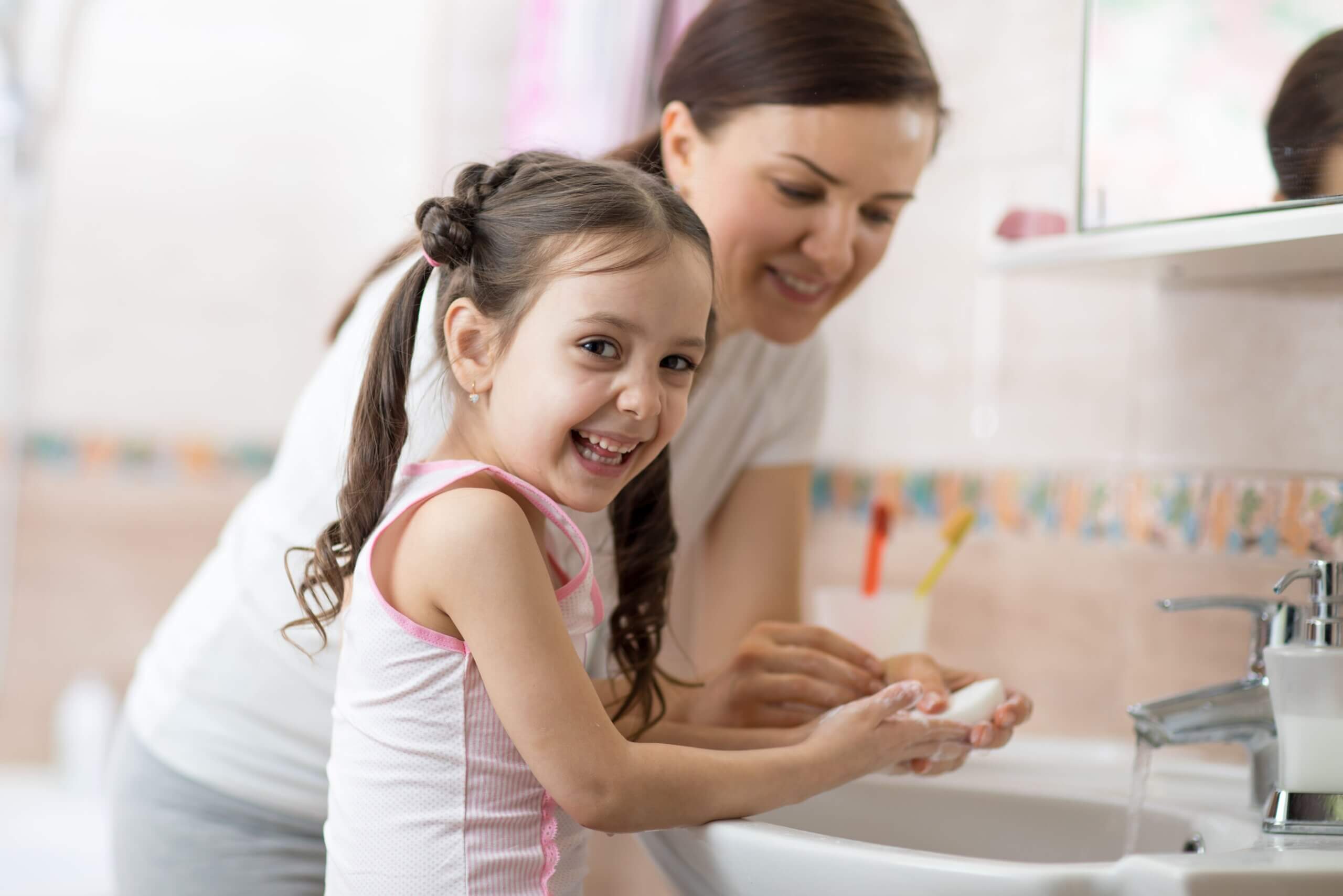 A mother and daughter washing their hands together.