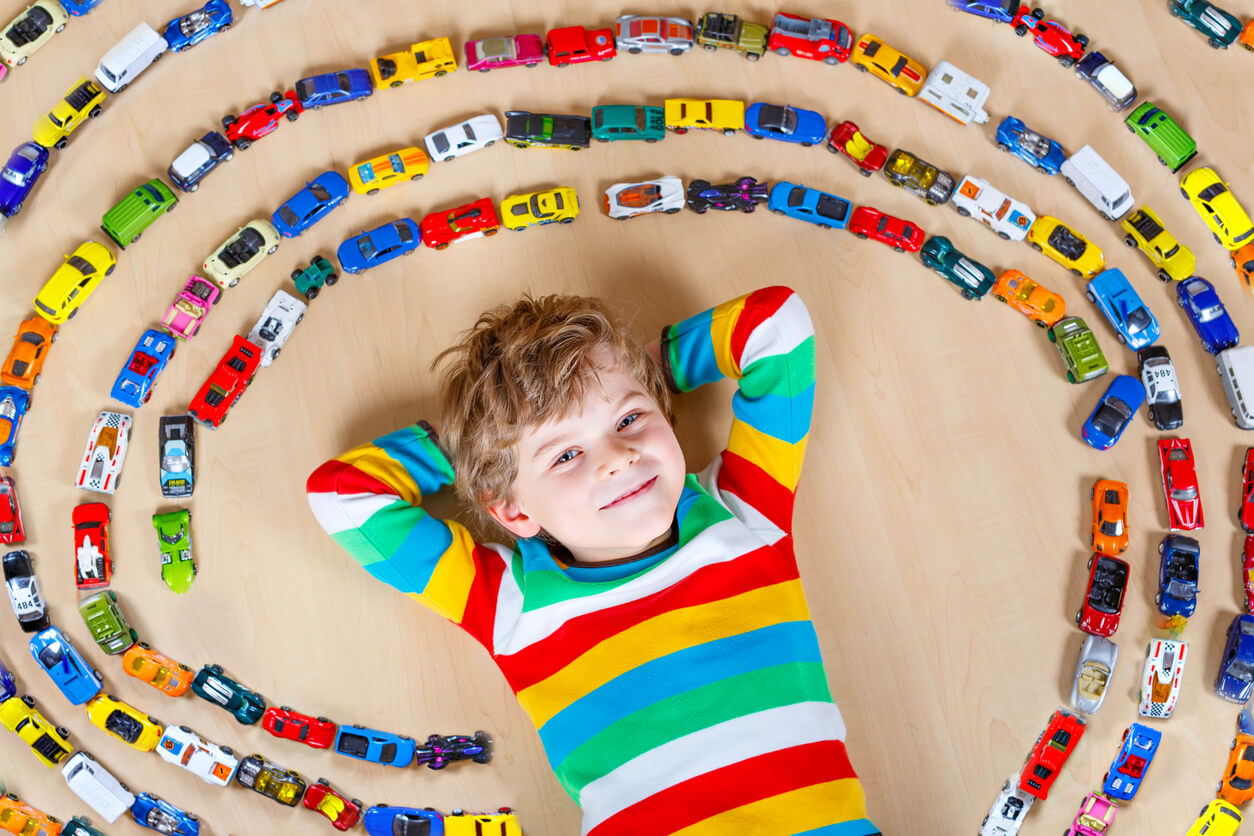 enfant allongé sur le sol avec spirale collection de voitures voitures petites voitures couleurs heureux