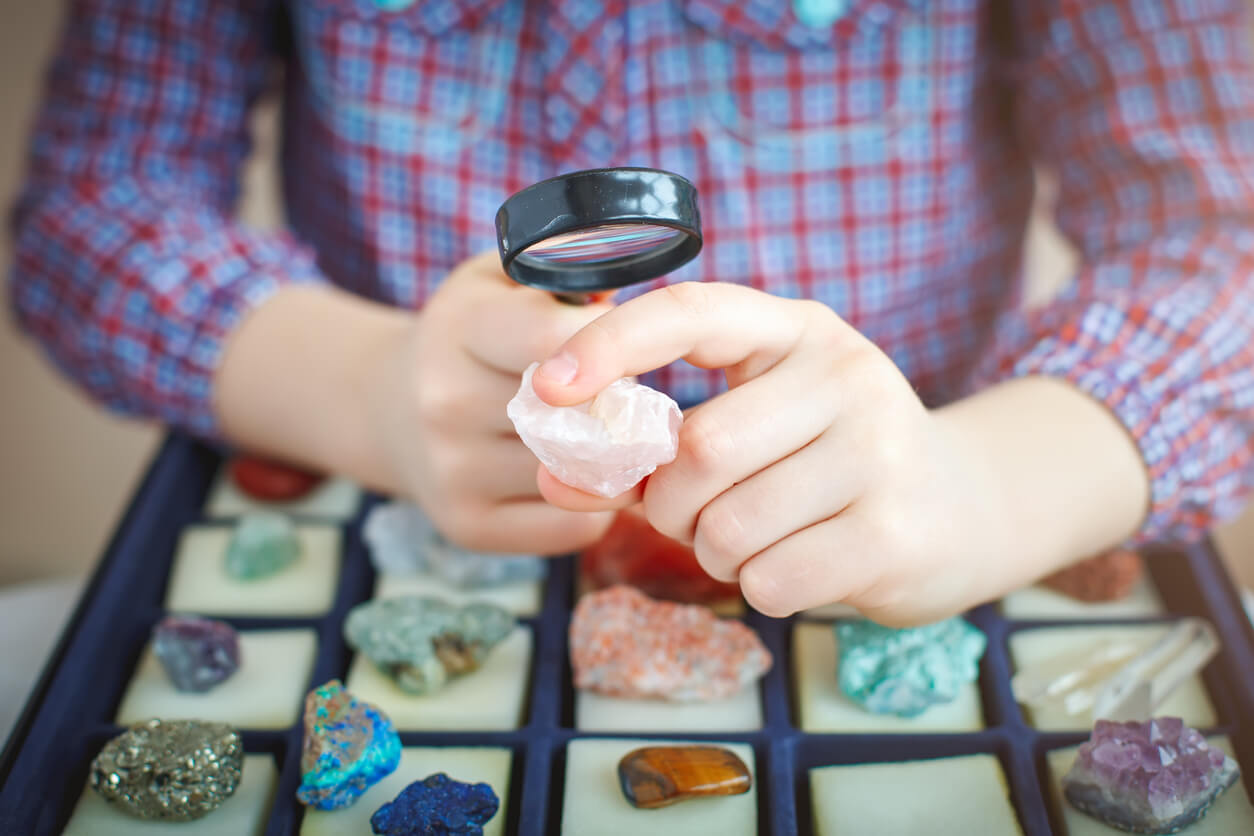 il bambino valuta con una lente d'ingrandimento le sue pietre collezione di rocce hobby di geologia