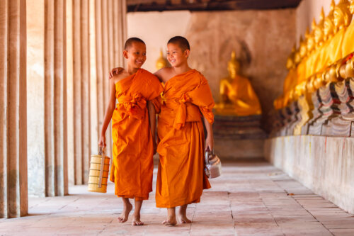 pequenos monjes budistas caminan conversan alegres por galeria del templo