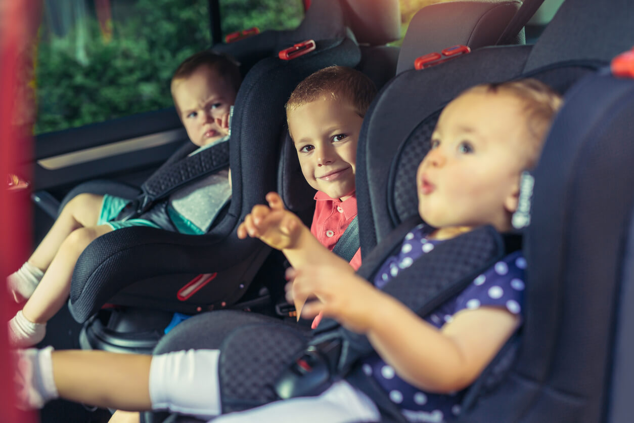 3 enfants installés à l'arrière d'une voiture.