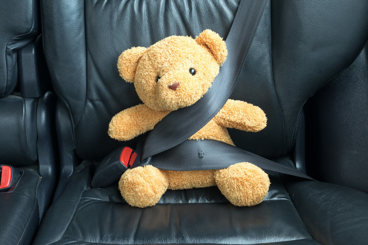Une peluche attachée dans une voiture.