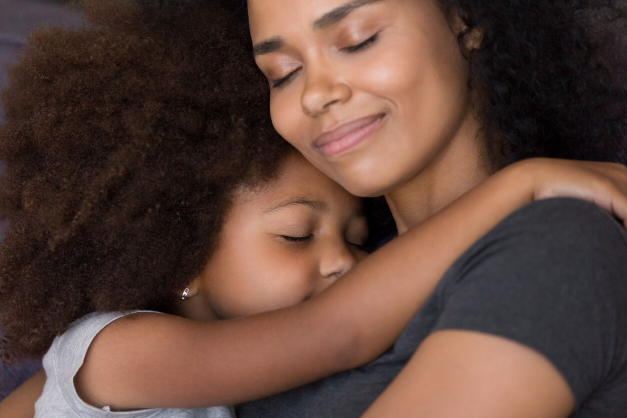 A black mother and her daughter in a tender embrace.