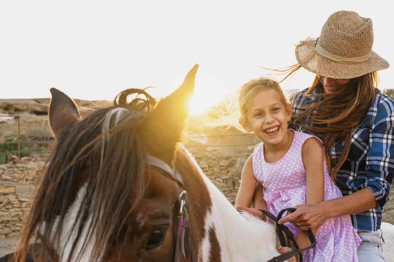 mère et fille montent à cheval dans le champ du coucher du soleil