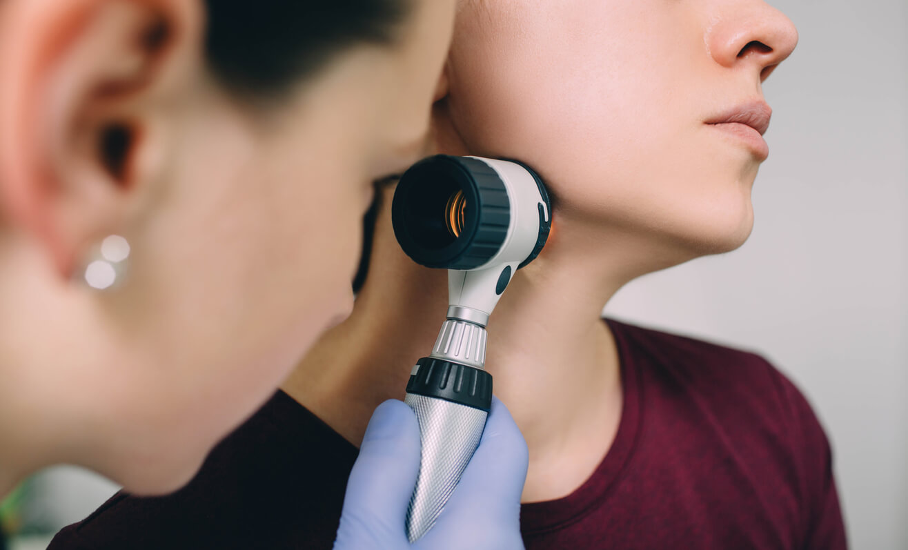Un médecin dermatologue évalue un acrochordon avec une femme dermatoscompio de pluie