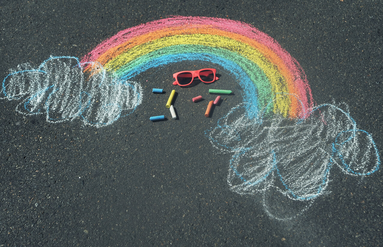 arcobaleno di gesso che disegna sul pavimento con occhiali e gessetti