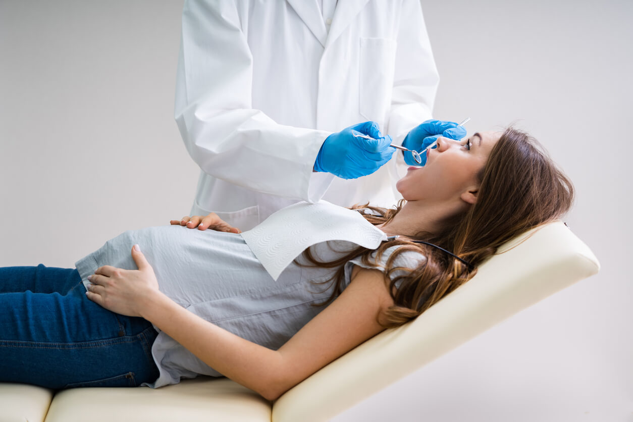 mujer embarazada examinada control dentista sillon consultorio odontologico profesional instrumental manos guantes