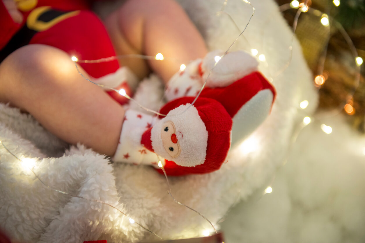 pies de bebe acostado junto al arbol de navidad disfraz de papa noel