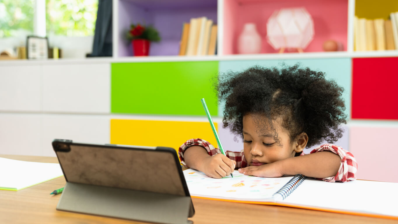 nina aprende lectoescritura con tableta cuaderno lapiz aprendizaje virtual en casa