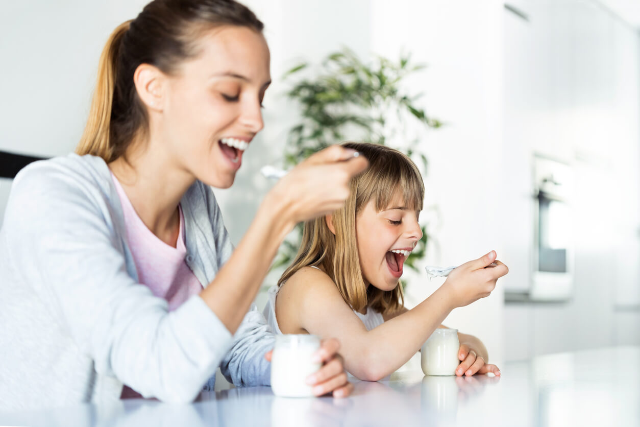 maman et fille mangent un pot en verre de yaourt sur la table de la cuisine