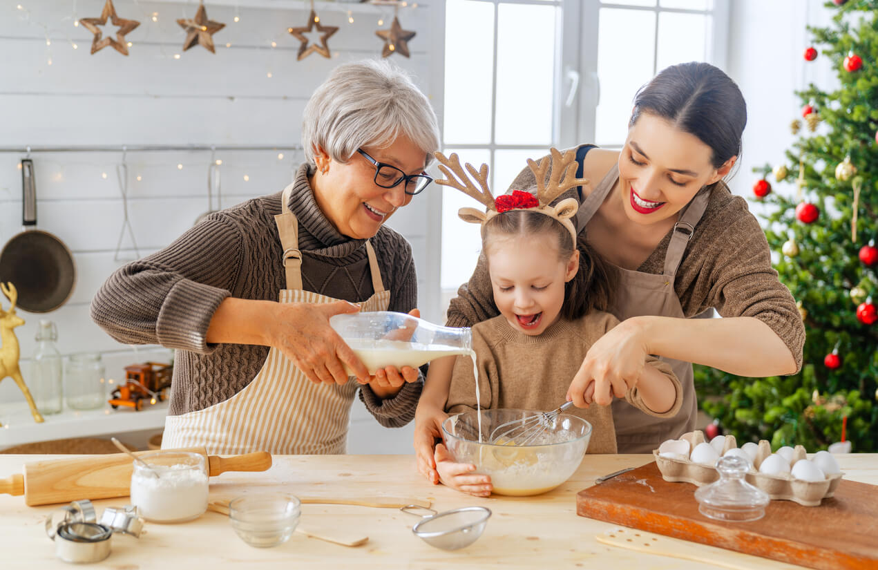 Três gerações preparando biscoitos na cozinha.