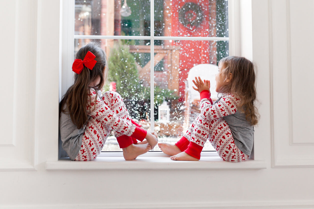 dia de navidad ninas pijamas miran nevar por la ventana invierno frio nublado copos de nieve