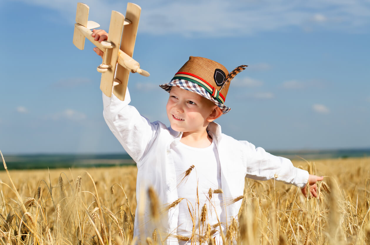 nino planea avion de madera en el campo eslavo