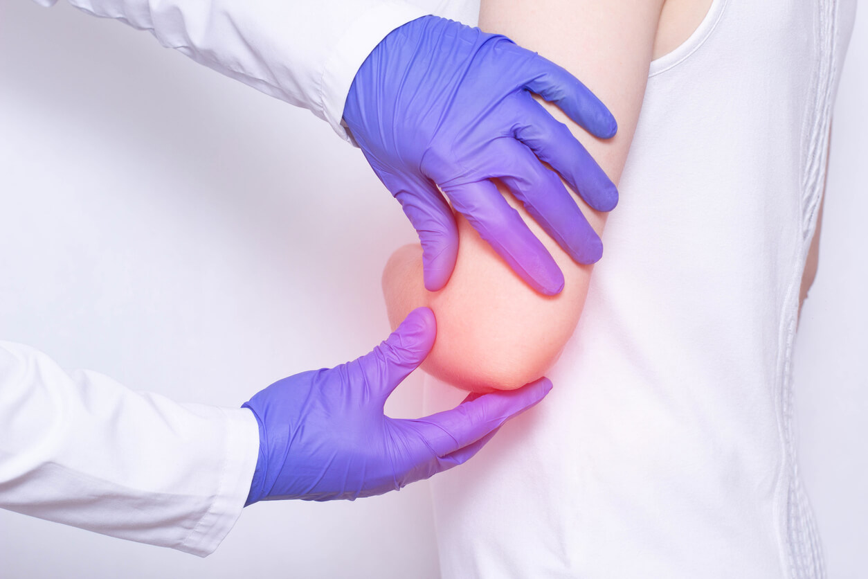 un médecin ganté examine un enfant souffrant de douleur au coude, d'épitrocléite, de bursite, de luxation