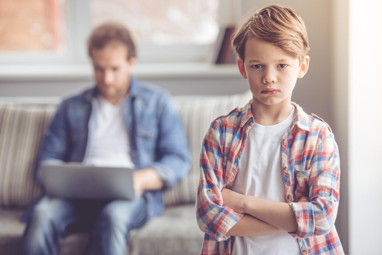 Un enfant triste car son père l'ignore devant un écran. 