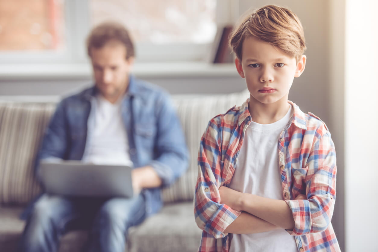 Un enfant triste car son père l'ignore devant un écran.