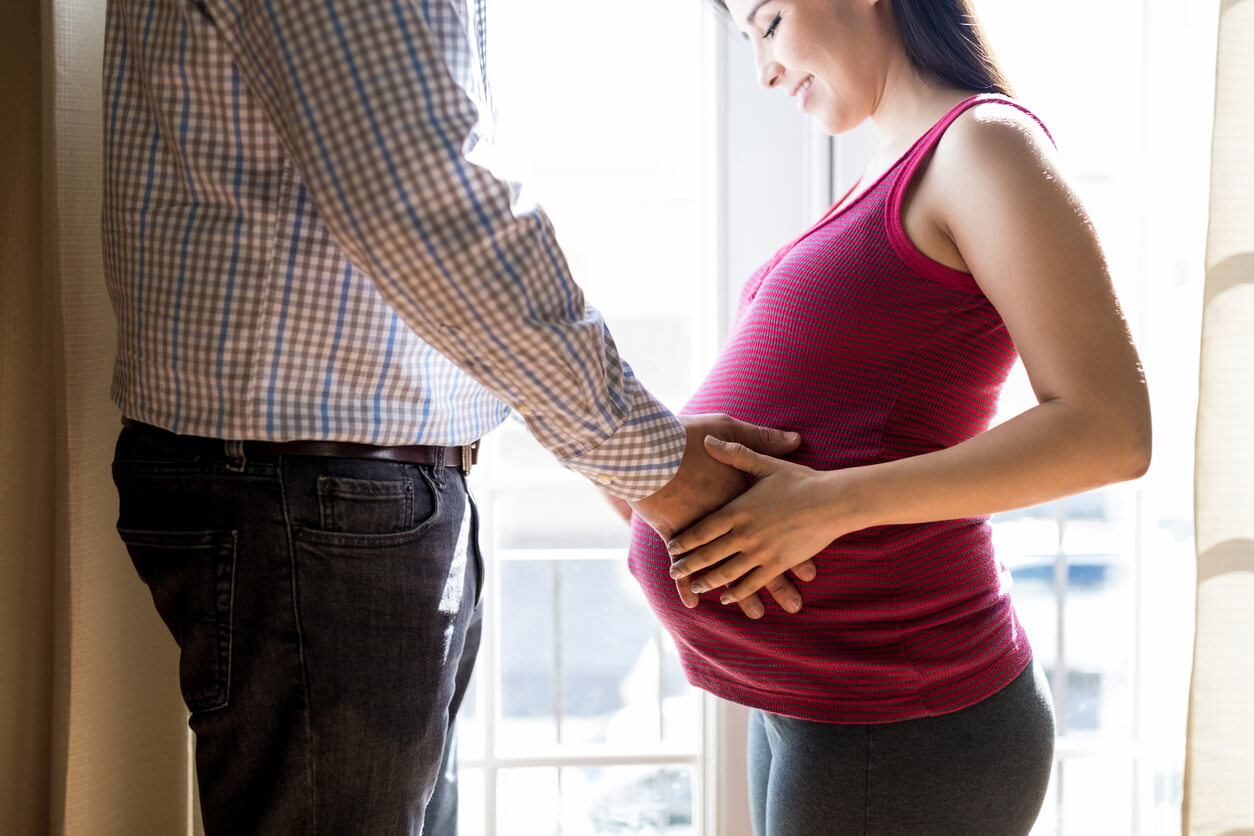 le couple perçoit les premiers mouvements fœtaux du bébé mains sur le ventre de la femme enceinte
