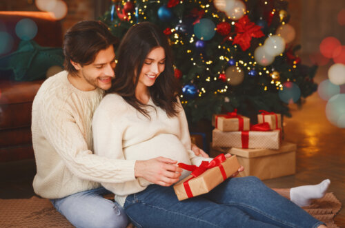 mujer embarazada pareja hombre marido obsequio presente regalo de navidad junto al arbol papa noel