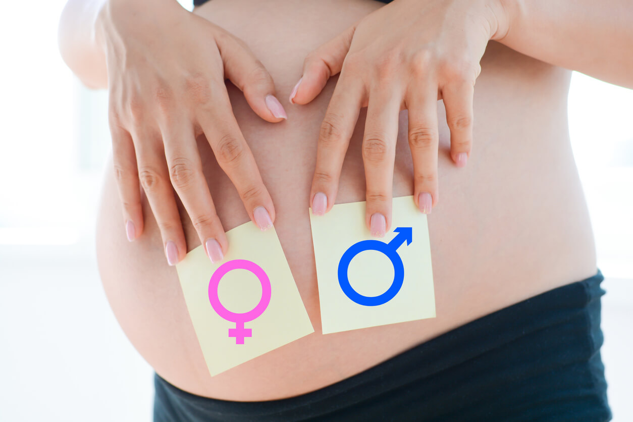 Une femme enceinte avec des cartes du sexe de l'enfant sur son ventre.