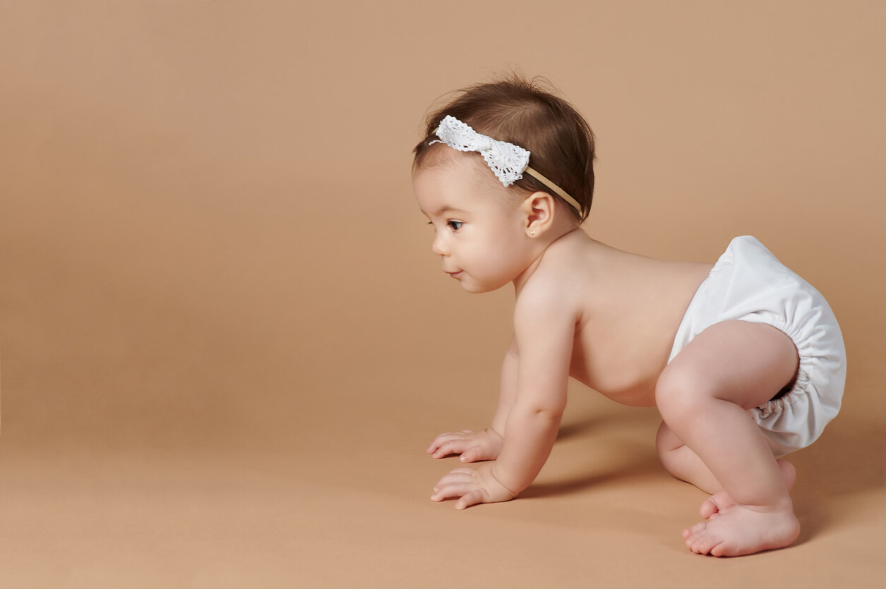 A baby girl in a diaper learning to crawl.