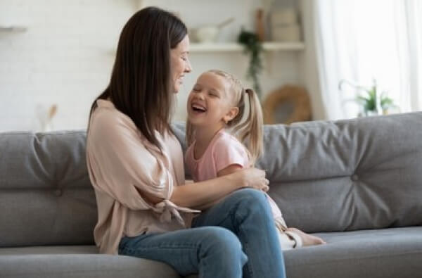 A mother and daughter laughing together on the couch.