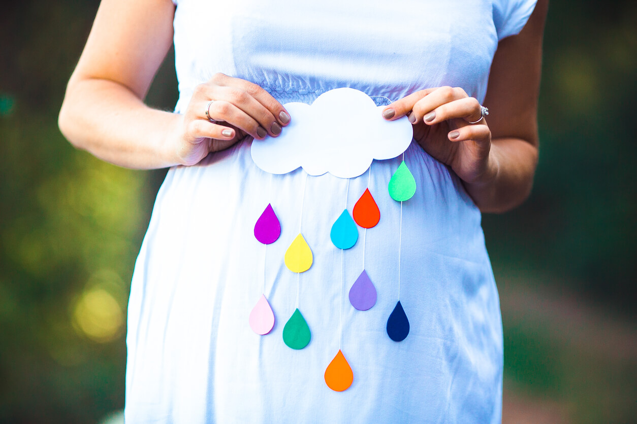 nube y gotas de lluvia de papel colores sobre vientre embarazada