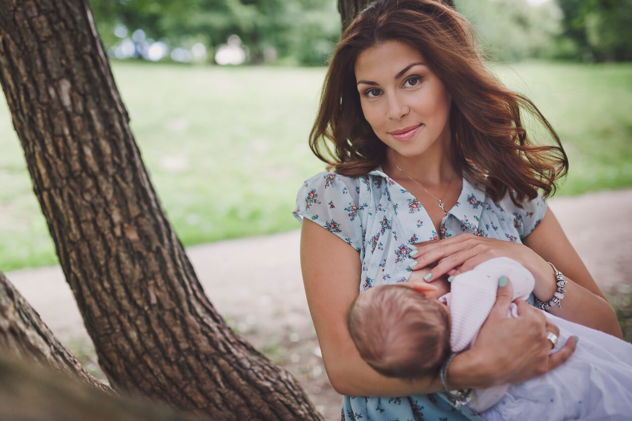 Une maman qui allaite son bébé dans un parc.