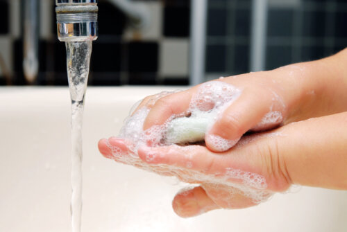 manos de niño pequeno que se lavan con agua y jabon bano lavatorio