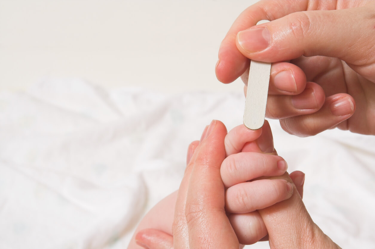 Un adulte qui lime les ongles d'un bébé.