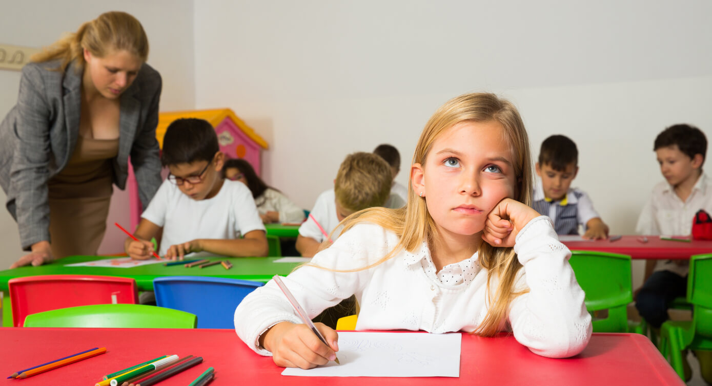 nina duda como se escribe una palabra en el pupitre de la escuela