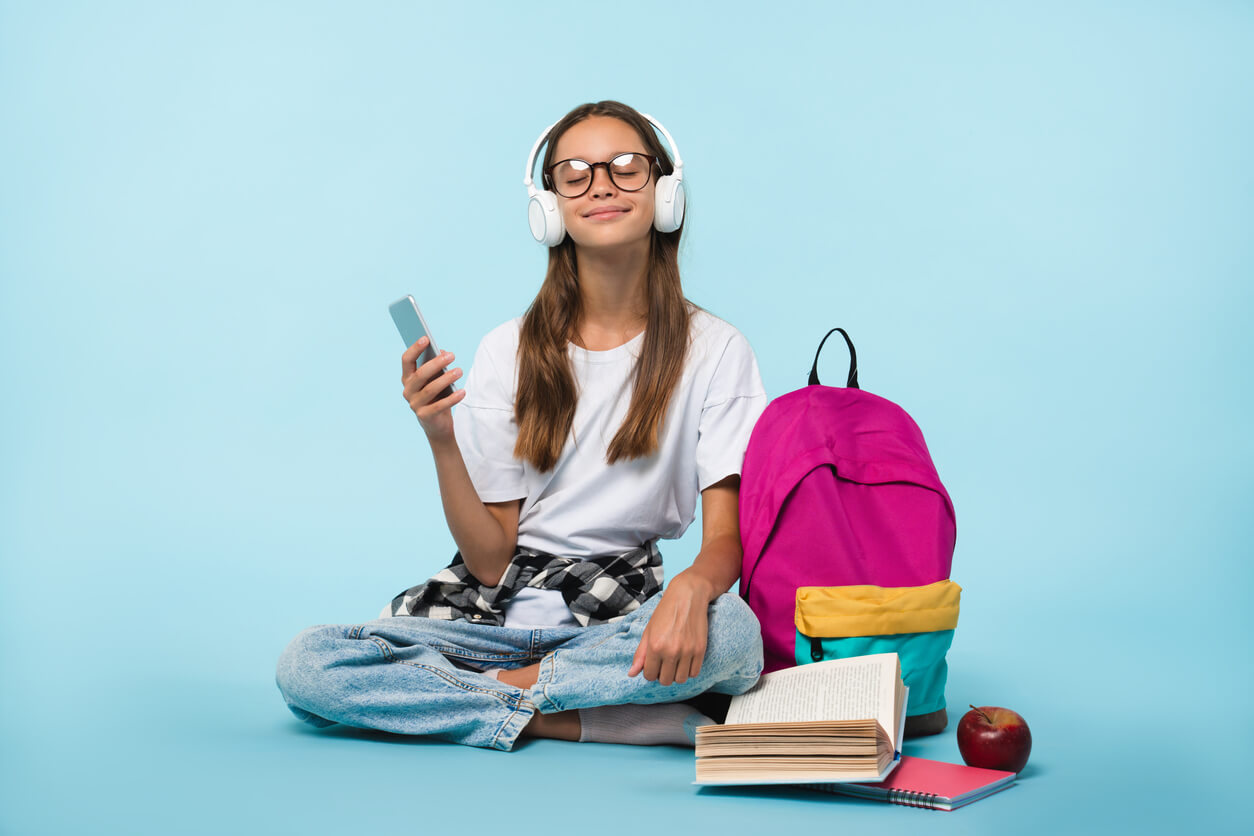 adolescente con utiles y mochila escolar aprende ingles escucha musica en su telefono movil