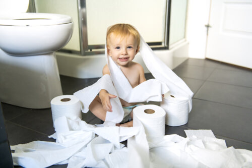 nino en el suelo del bano envuelto en rollo de papel higienico