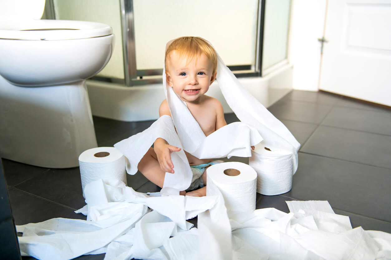 nino en el suelo del bano envuelto en rollo de papel higienico