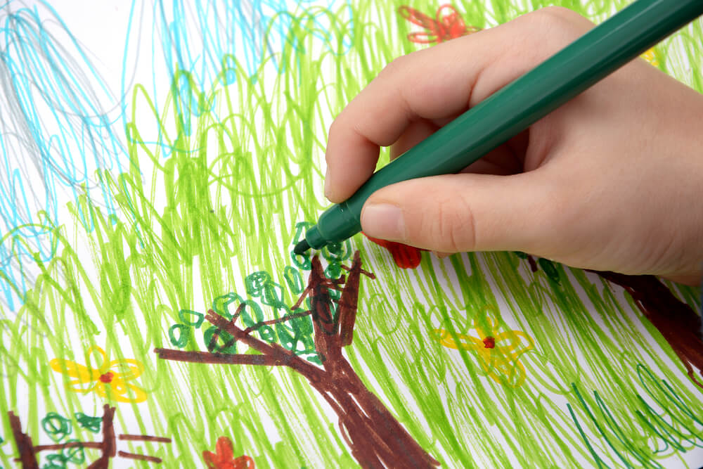 A child drawing a tree with markers.