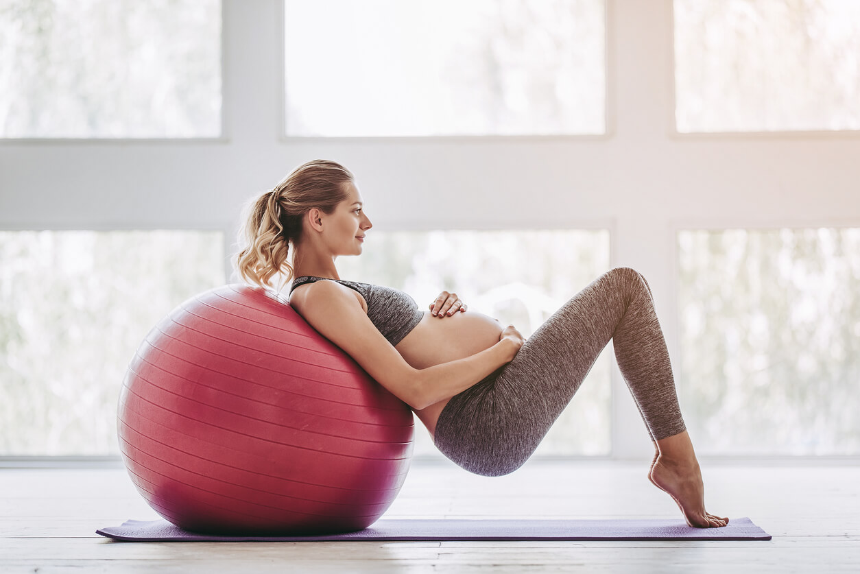 mujer embarazada practica ejercicios de yoga pilates con pelota