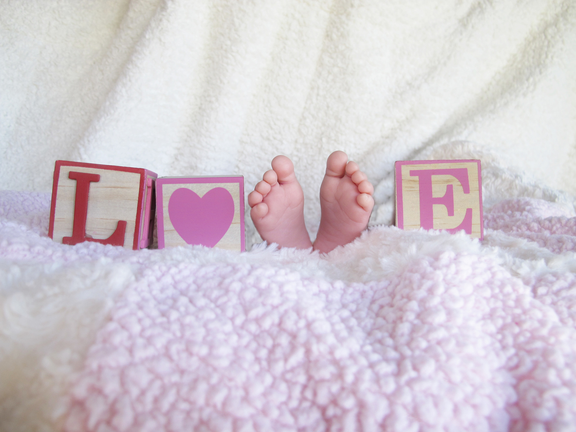 palabra amor en ingles love escrita con cubos de madera y pies de bebe sobre manta de cordero