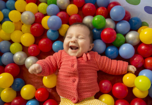 bebé posa sonrie en pelotero bolas de colores