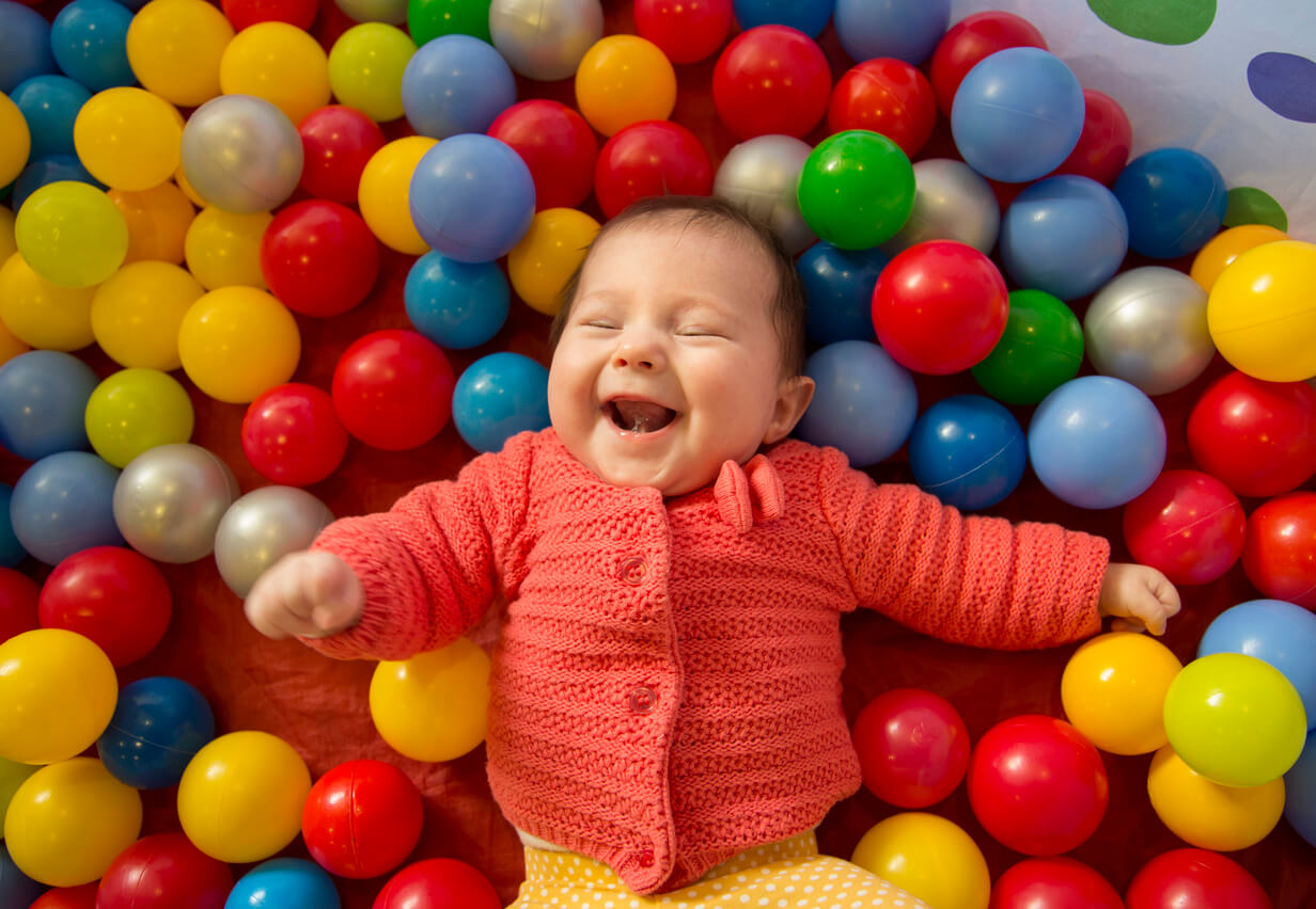 bebé posa sonrie en pelotero bolas de colores