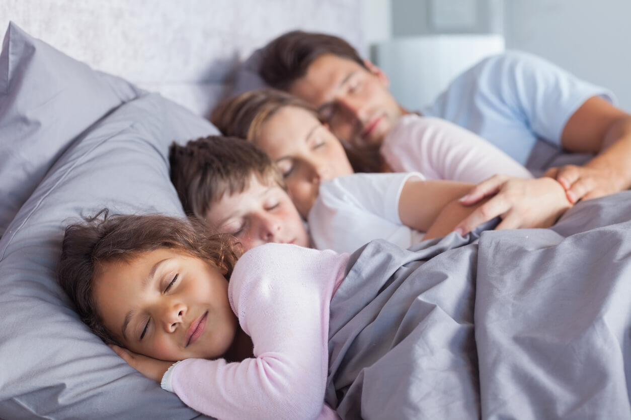 A family of four sleeping together in the same bed.