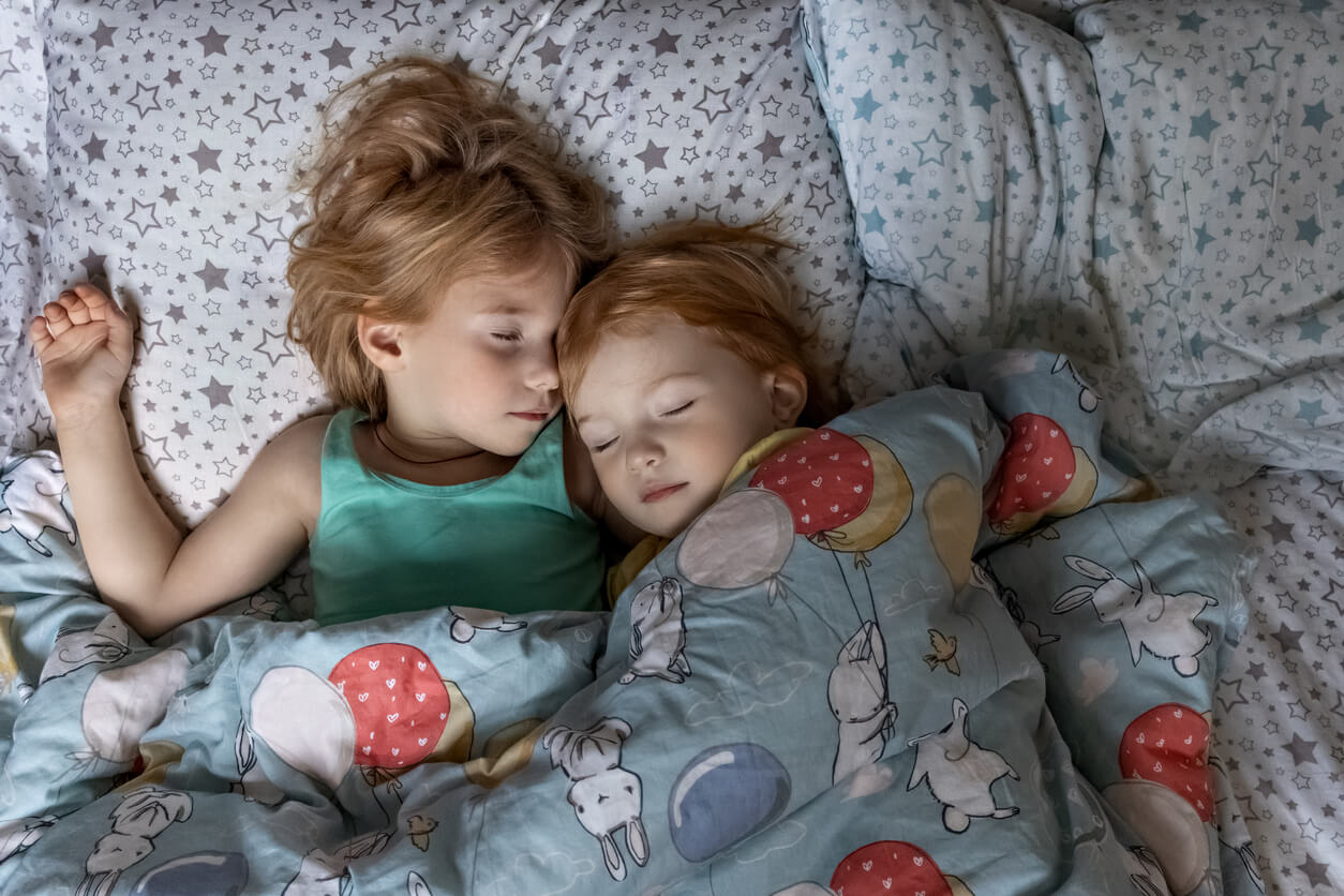 dos hermanas pequenas duermen juntas en la misma cama