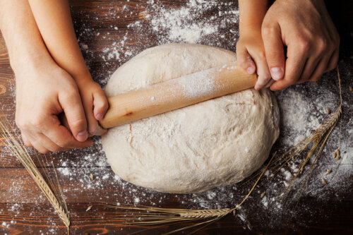 manos de adulto y de nino amasan masa de pan o pizza brotes de sesamo