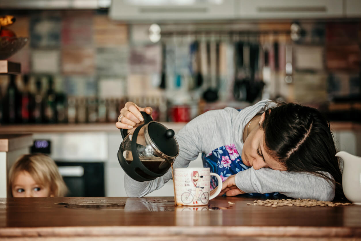 En sliten mor skjenker seg kaffe.