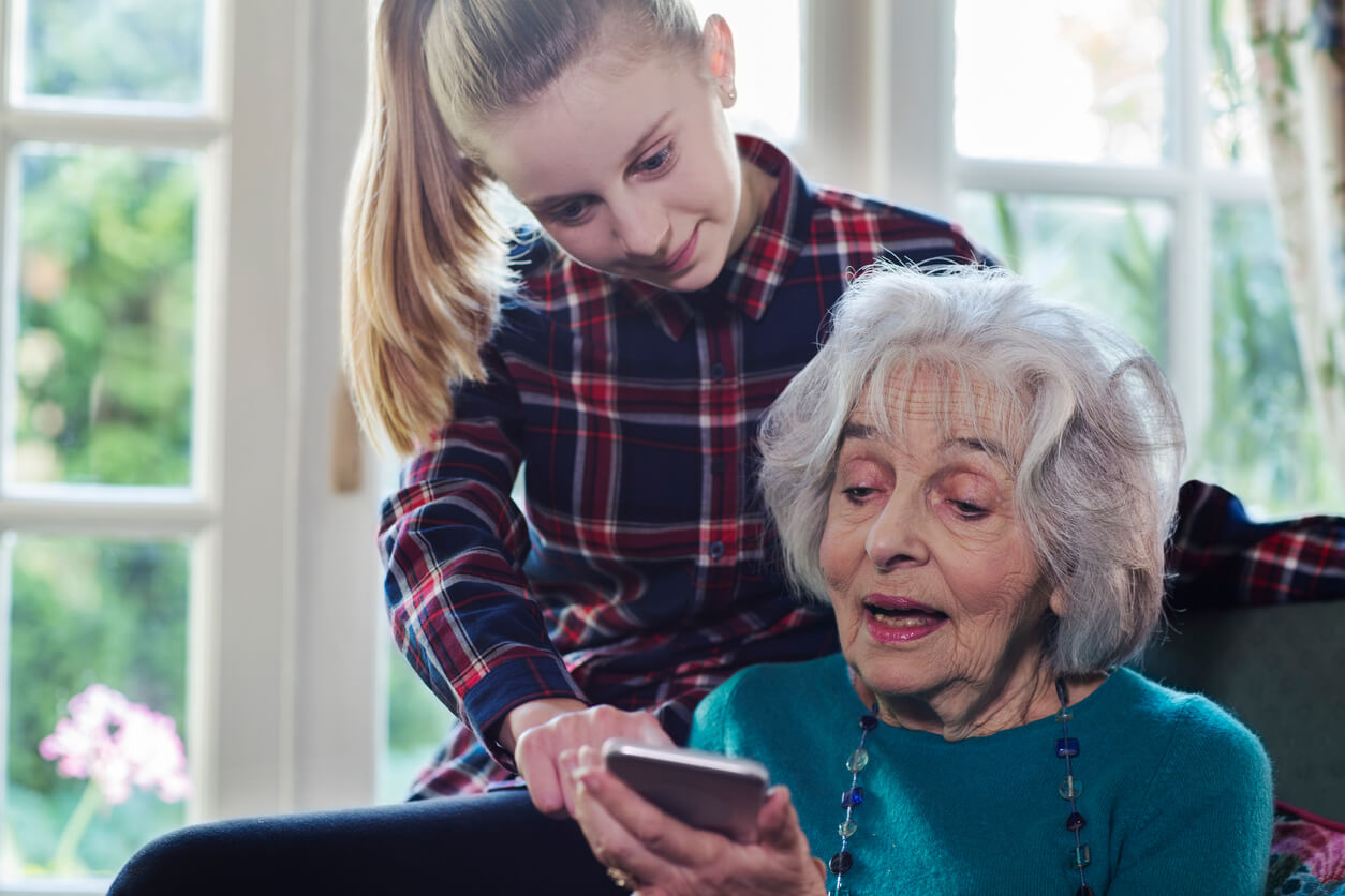 joven nieta le ensena a su abuela a usar el smartphone