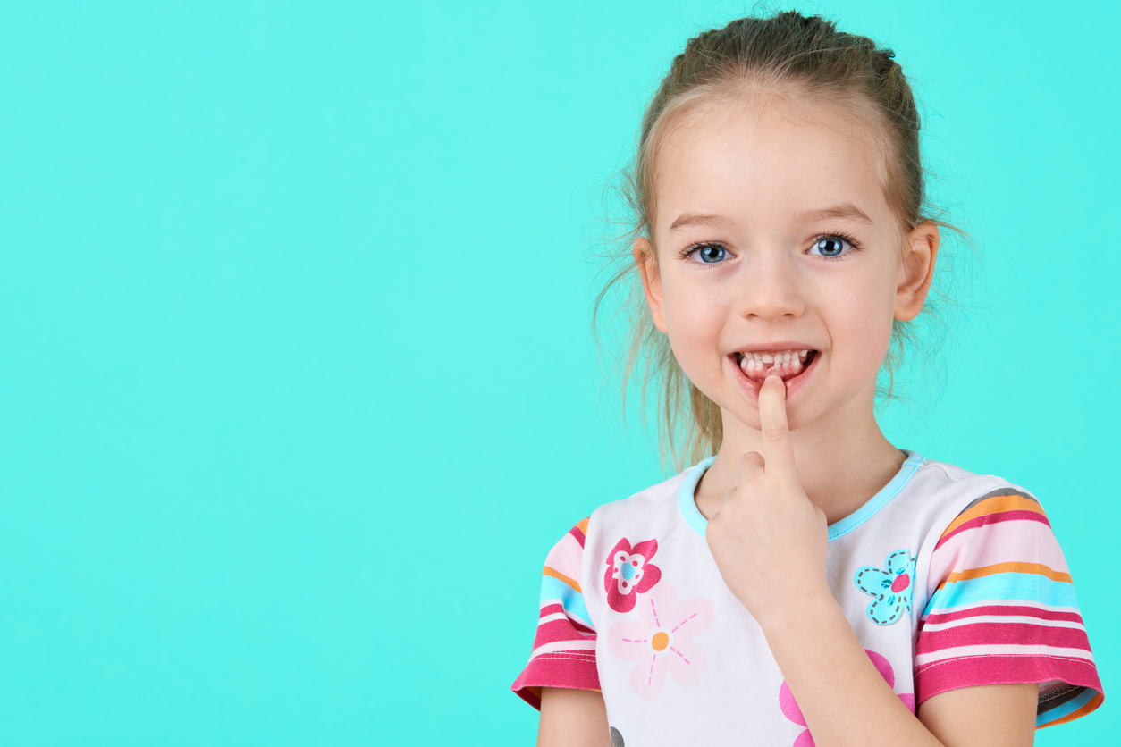 Adorable School age girl showing off gap from missing Tooth