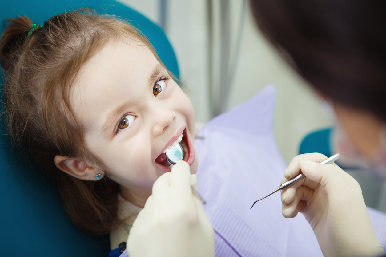menina sentada na cadeira do dentista para controle de check-up feliz sorriso luvas espelho de mão e elemento instrumental pontiagudo